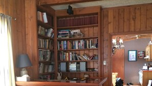 Ein Zimmer mit Holzwänden, einer Bar, einem Bücherregal und einem Essbereich.