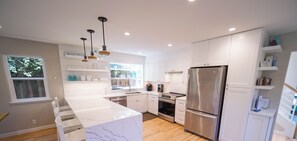 A modern kitchen with white cabinetry, a marble island, and stainless steel appliances.