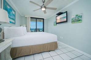 Ein Hotelzimmer mit Bett, Deckenventilator, Fernseher und einem Balkon mit Blick.