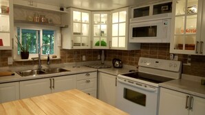 A kitchen with white cabinets, a microwave, an oven, and a sink. - Private cozy cottage on Bobs Lake with boat launch (Maberly)
