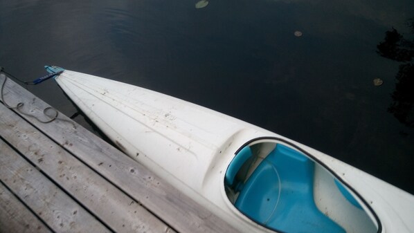 A white canoe docked at a wooden pier with a blue interior.