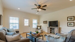 A living room with a ceiling fan, a television, and a coffee table. - A Tennessee Tiny House: A Quiet Readaway Retreat for Rest & Reconnection (Clarksville)