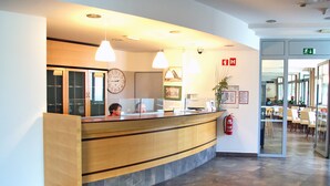 Un mostrador de recepción con un reloj, luces colgantes y un extintor.