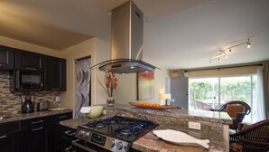 Une cuisine moderne équipée d’une cuisinière à gaz, d’un four, d’un four à micro-ondes et de meubles de rangement aux couleurs sombres.