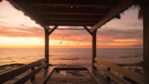 Une structure en bois avec un banc d’où l’on peut admirer l’océan au coucher du soleil.