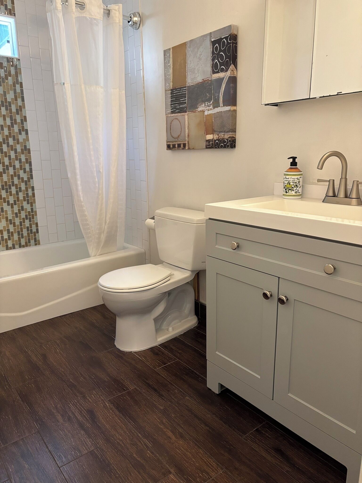 A bathroom with a toilet, bathtub, and a sink with a mirror above it.