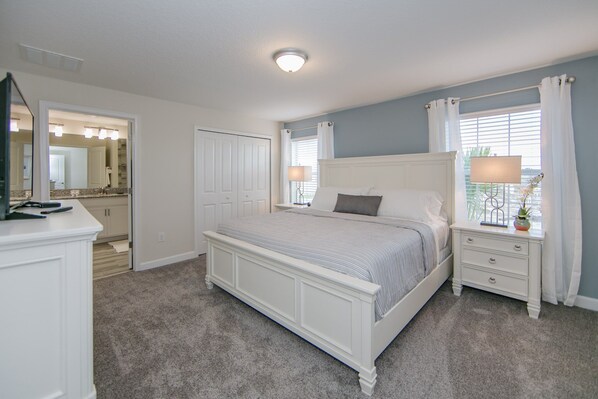 A bedroom with a bed, nightstands, a dresser, and a bathroom visible through an open door.