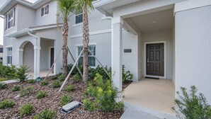 A two-story house with a covered porch, a palm tree, and a well-maintained garden. - (JA4907)  Home 4/3 Private Pool, Lake & Free Waterpark (Kissimmee)