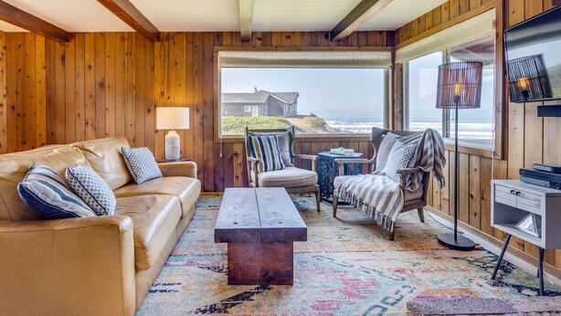 A cozy living room with a leather sofa, a wooden coffee table, and a view of the ocean.