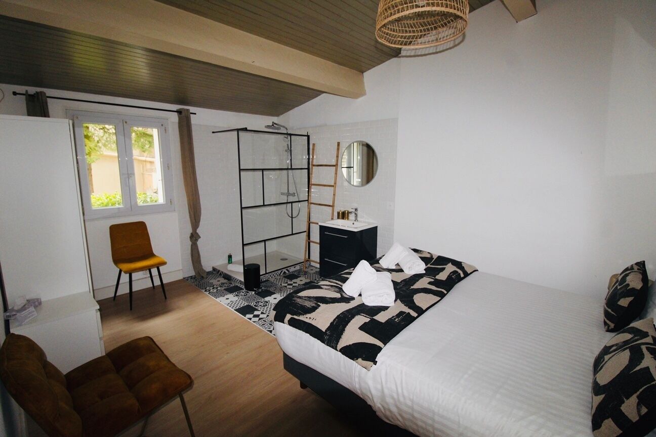 Ein Schlafzimmer mit einem Bett, einem Sessel, einem Kleiderschrank, einem Spiegel und einem Fenster.