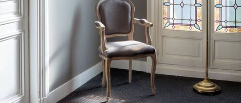 A corner room with a chair, a lamp, and a door with stained glass windows.
