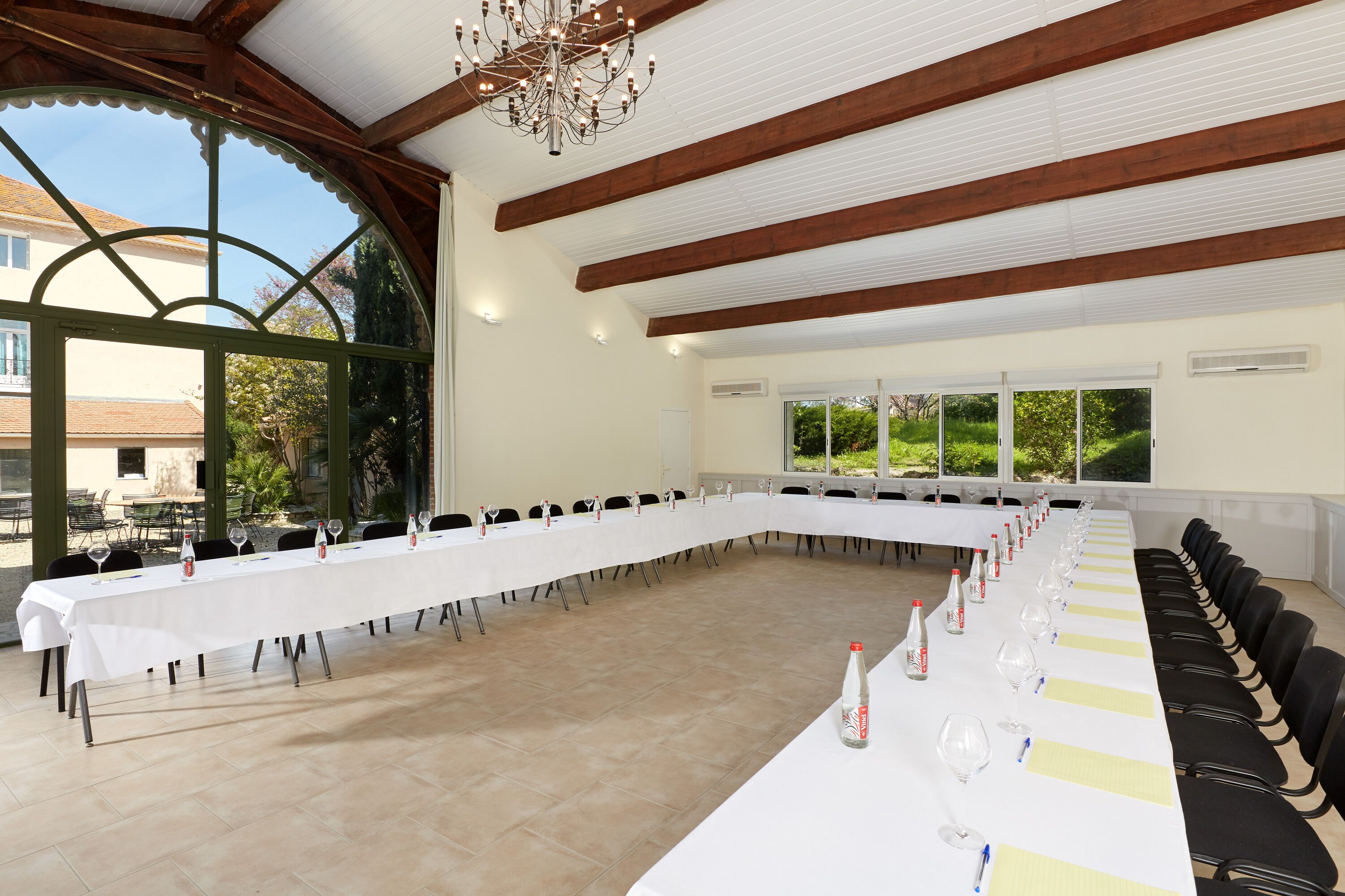 Une salle de conférence avec une longue table, des chaises et un lustre.