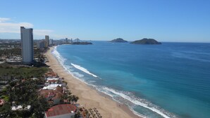 A coastal cityscape with a wide beach, high-rise buildings, and clear blue waters.