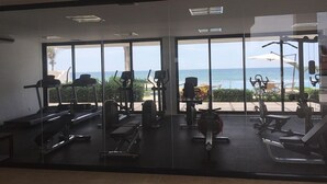 A gym with various exercise equipment and large windows offering a view of the ocean.