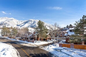 Un quartier résidentiel enneigé, avec des maisons, une route et une montagne en arrière-plan.