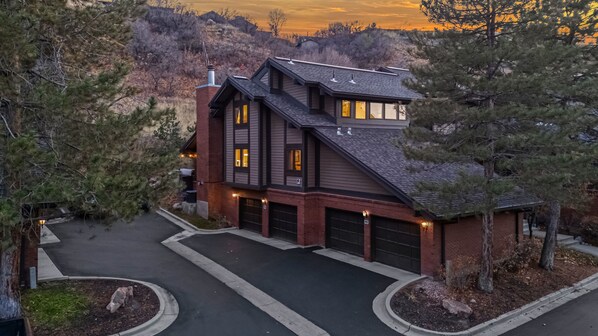 A two-story house with a garage, surrounded by trees and a driveway.