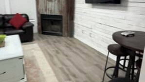 Una sala de estar moderna con chimenea, un sofá, una mesa de centro y un televisor montado en la pared.
