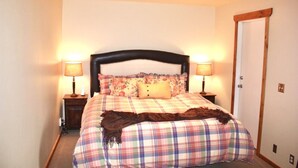 Un dormitorio con una cama, dos mesitas de noche y una puerta.