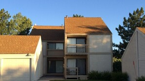 Un edificio residencial de dos pisos con garaje, porche delantero y un pequeño jardín frontal.