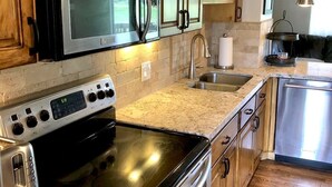 Una cocina con gabinetes de madera, electrodomésticos de acero inoxidable, encimera de granito y horno empotrado.
