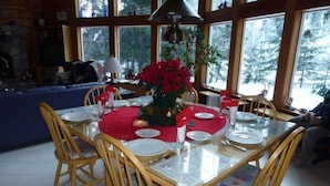 A dining area with a glass table, wooden chairs, and a red tablecloth.