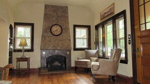 Una habitación con chimenea, suelo de madera, un reloj y dos sillones.