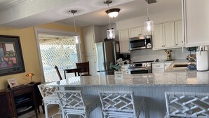 A kitchen with white cabinets, a large island with bar stools, and stainless steel appliances.