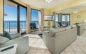 Une chambre d’hôtel avec balcon, un canapé, une télévision et vue sur l’océan.