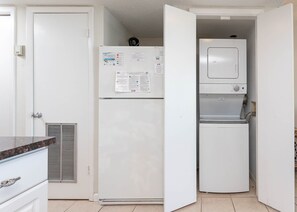 Een compacte keuken met een witte koelkast, een ingebouwd waterdispenser en een magnetron.
