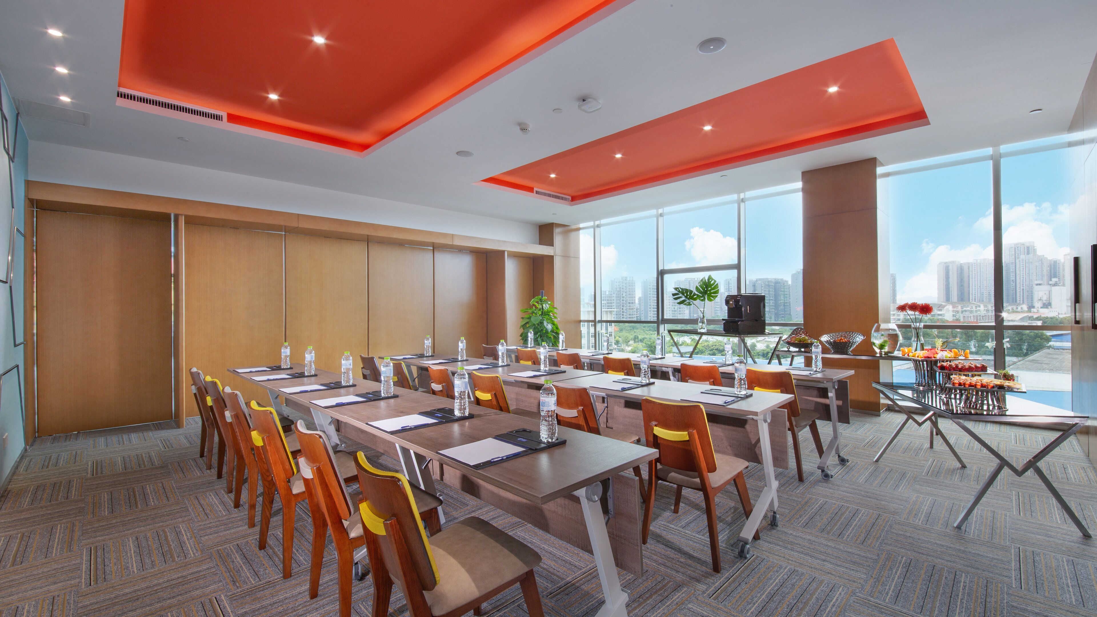 A modern conference room with a large table, chairs, and a city view through large windows.