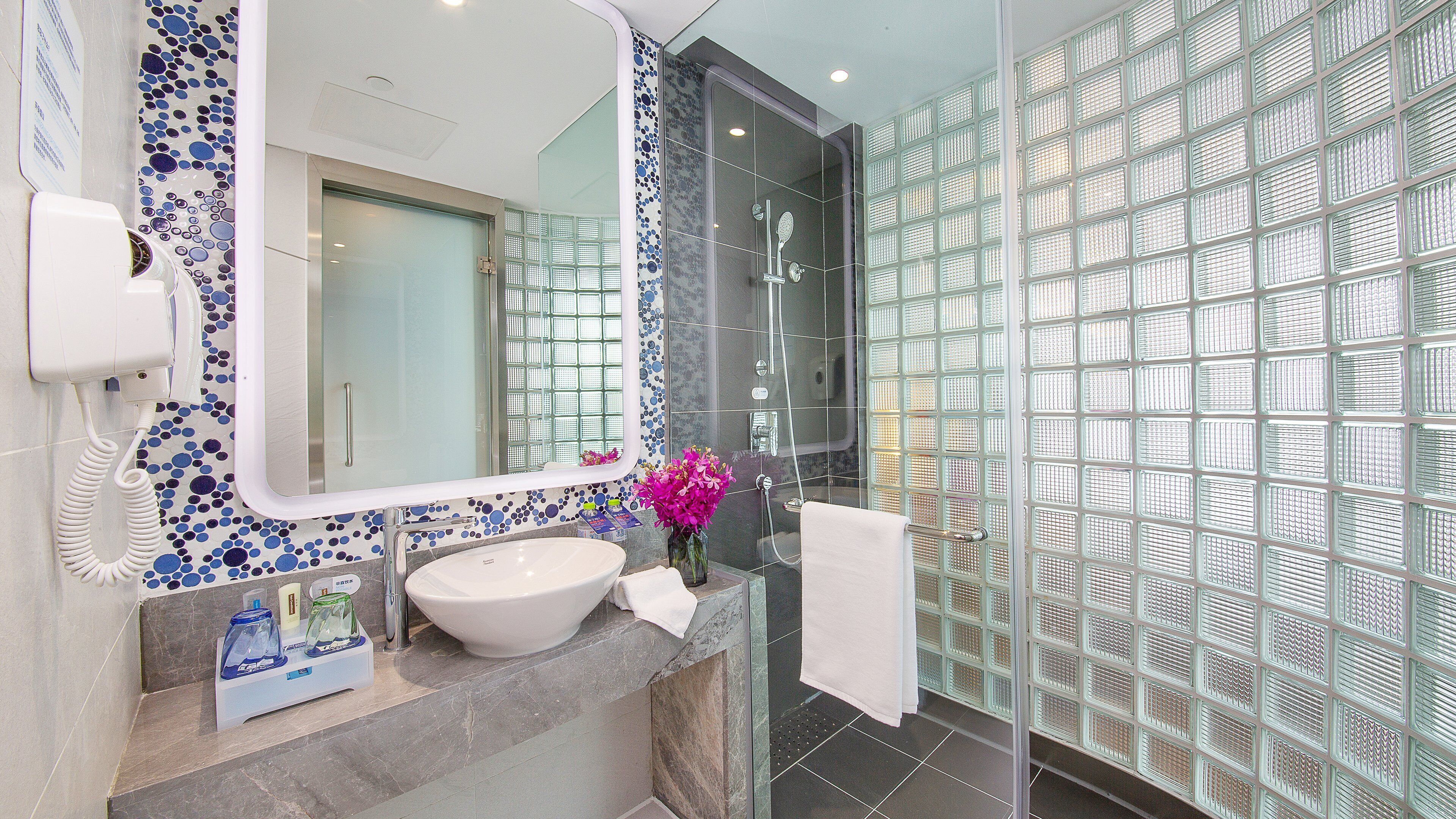 A bathroom with a large mirror, a sink, and a shower area.
