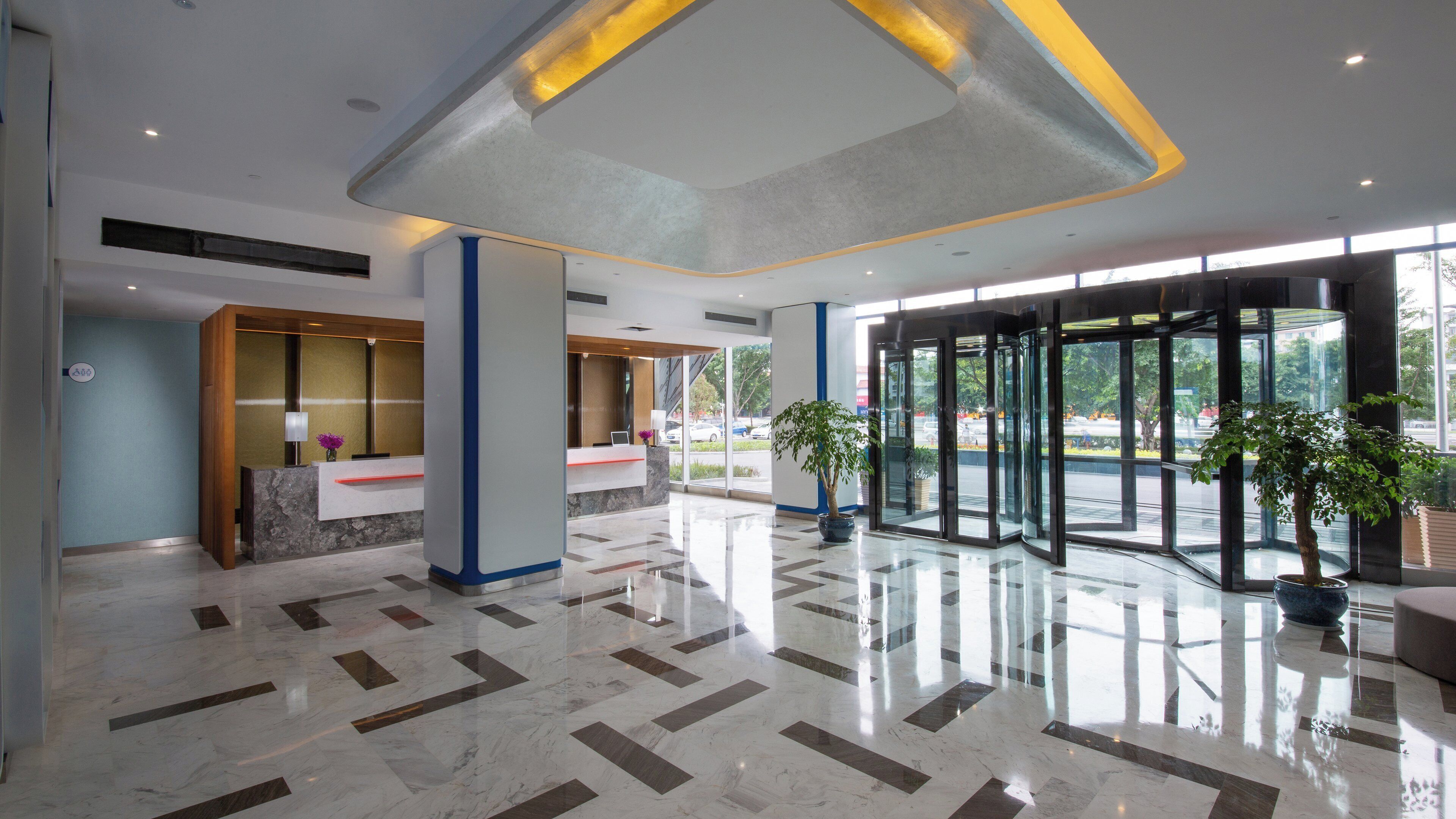 A modern lobby with a marble floor, glass doors, and a reception desk.