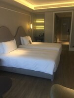 A hotel room with a large bed, a bedside table, and a chair.