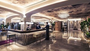 Eine großzügige Lobby mit einer Rezeption, einer Sitzecke und einem Kronleuchter.