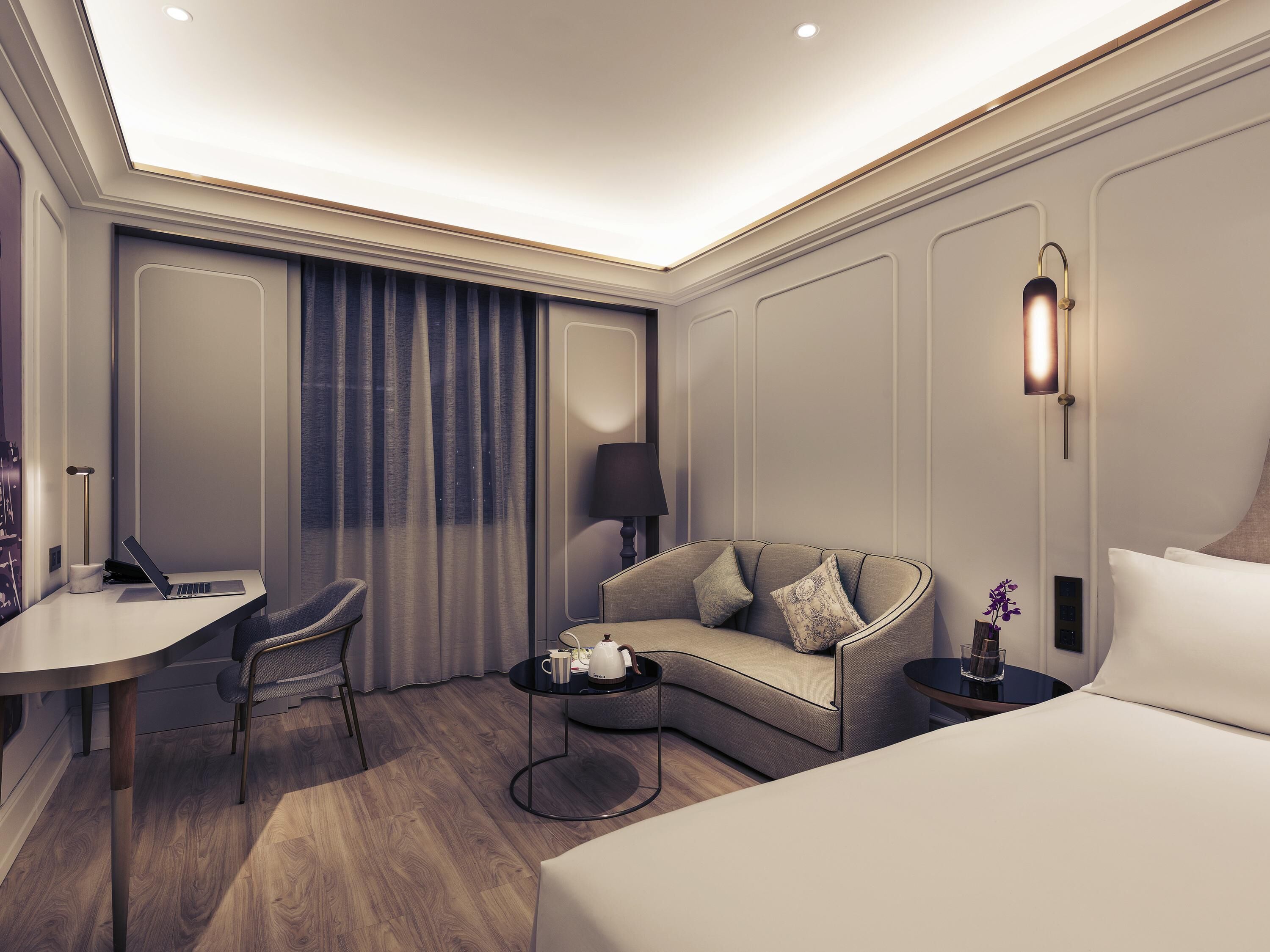 Una habitación de hotel moderna con escritorio, sofá, mesa de centro y cama.