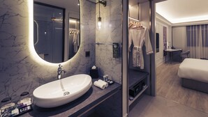 Ein modernes Hotelbad mit einem großen, ovalen Waschbecken, einem Spiegel und einer Duschkabine.