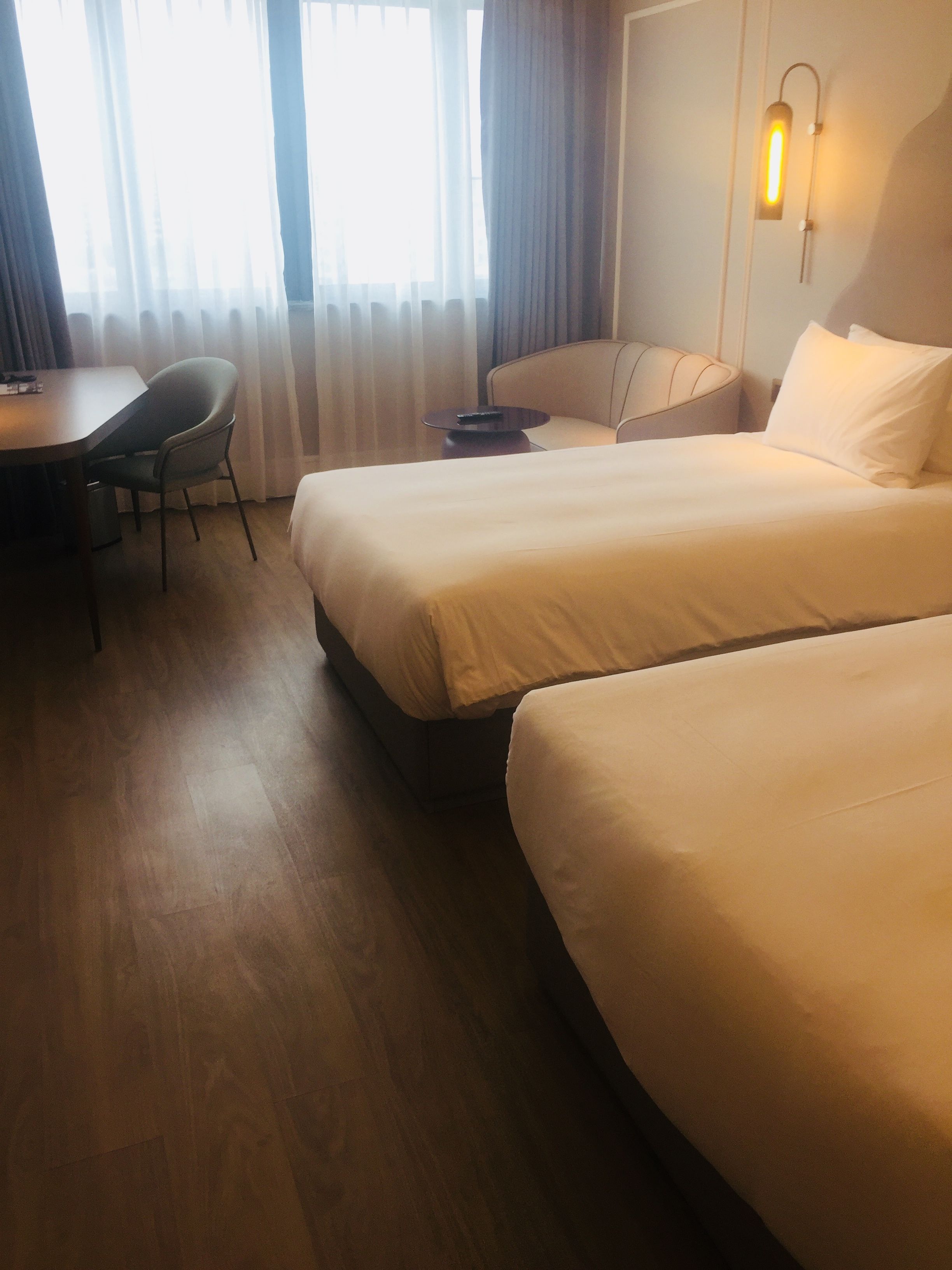 Una habitación de hotel con dos camas, un escritorio, una silla y una lámpara.