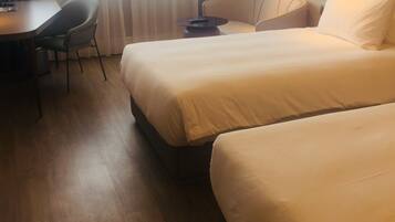 Una habitación de hotel con dos camas, un escritorio, una silla y una lámpara.