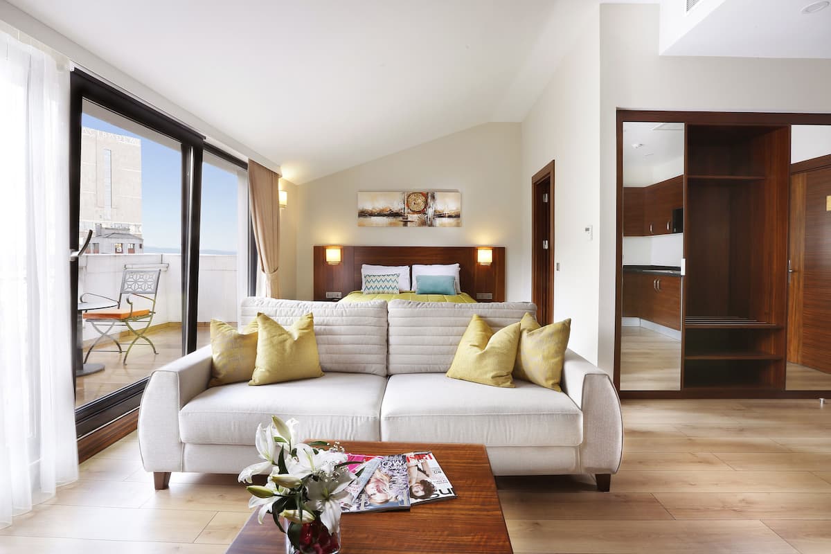 A modern living room with a sofa, coffee table, and a bed with a view.