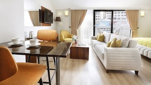 A modern hotel room with a dining area, a sofa, and a TV mounted on the wall. - The White Orient Hotel (Istanbul)