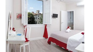 A bedroom with a bed, a desk, a chair, a window, and a door.