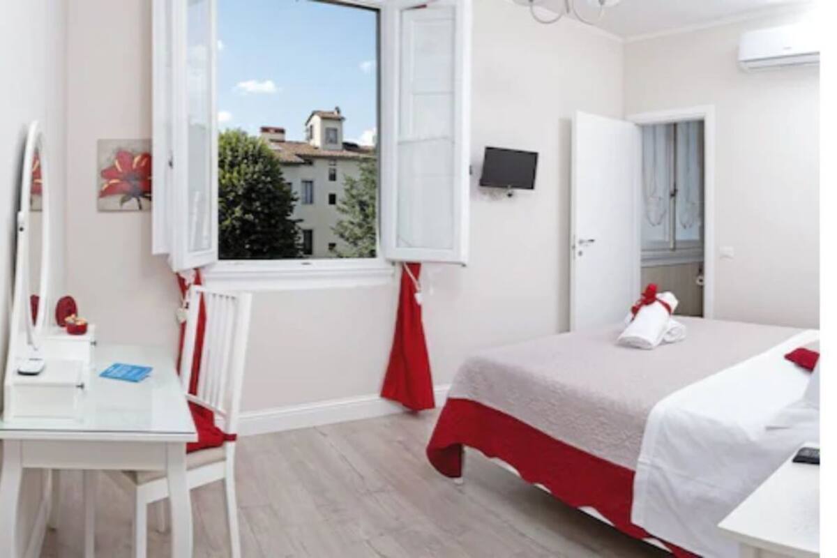Een slaapkamer met een bed, een bureau, een stoel, een raam en een deur.