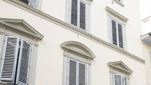 A row of parked motorcycles in front of a building with a wooden door and white shutters.
