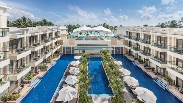 Een modern hotel met een centraal gelegen zwembad, meerdere balkons en uitzicht op de oceaan.
