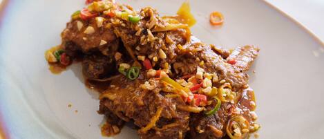 A plate of beef with vegetables and nuts.