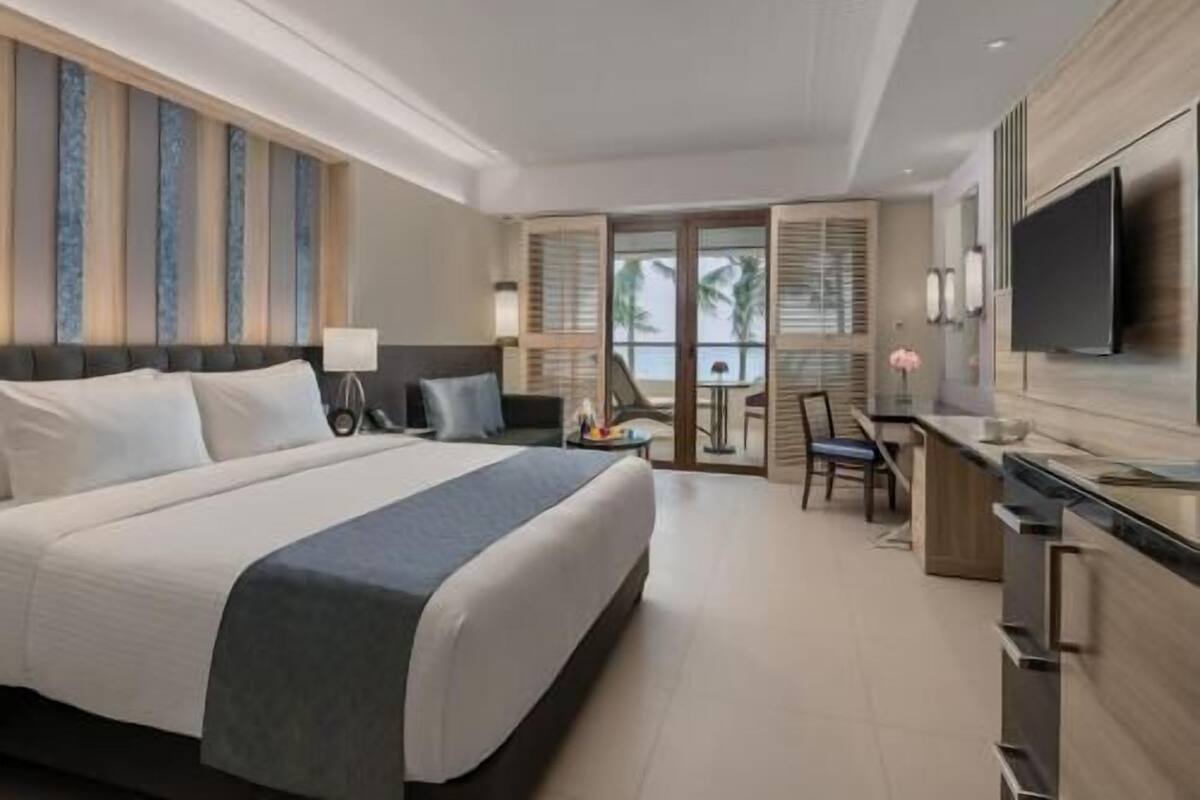 Una habitación de hotel moderna con una cama grande, un escritorio y un televisor.
