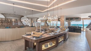 Een modern ontbijtbuffet met diverse keuzes, een uitzicht op zee en een stijlvol interieur.