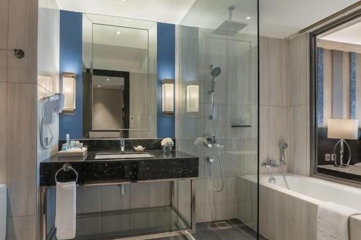 Un baño moderno con ducha de vidrio, un espejo grande y una bañera.