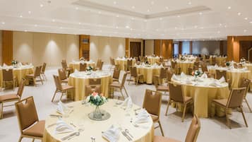 A large banquet hall with round tables set for dining, each with chairs and table settings.