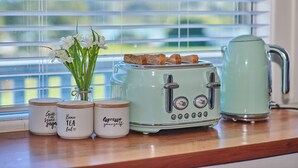 Eine Küchenarbeitsplatte mit einem Retro-Toaster, einem Wasserkocher und drei beschrifteten Gläsern.